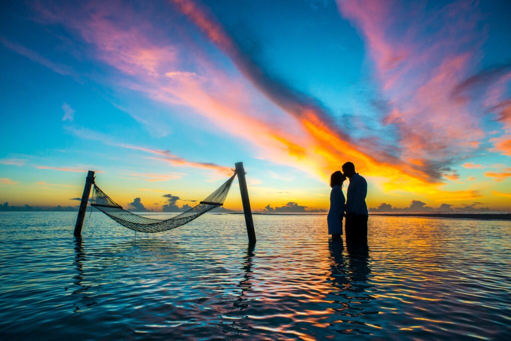 couple on romantic getaways in water under sunset with hammock in water