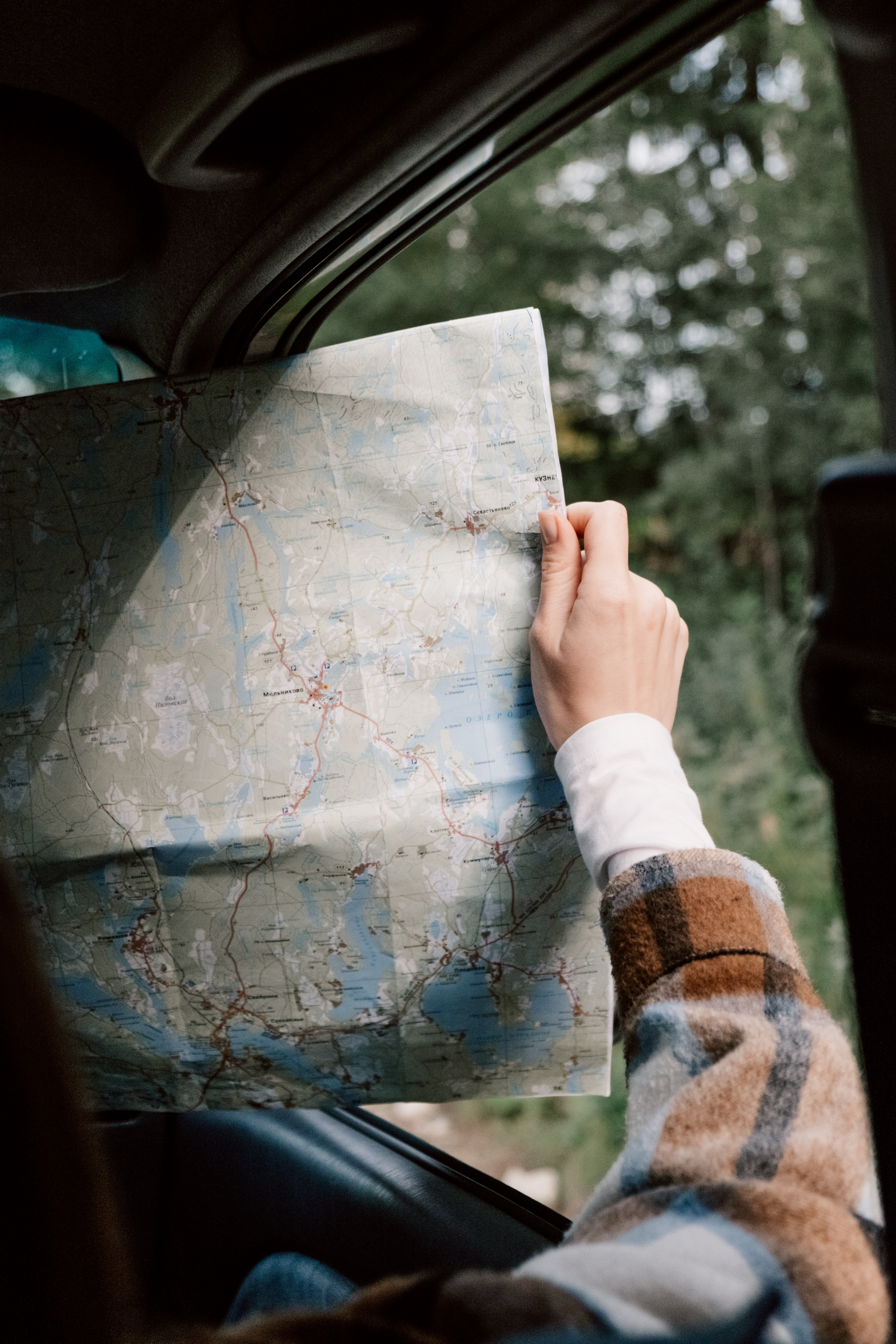 woman holds map in car for road trip tips