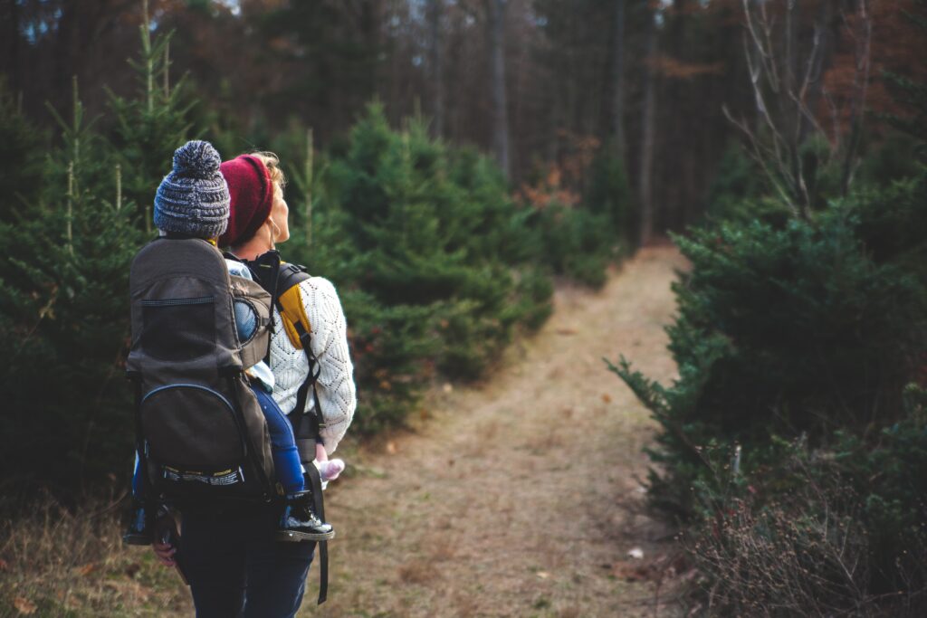 woman walks on trail during staycation with child on back