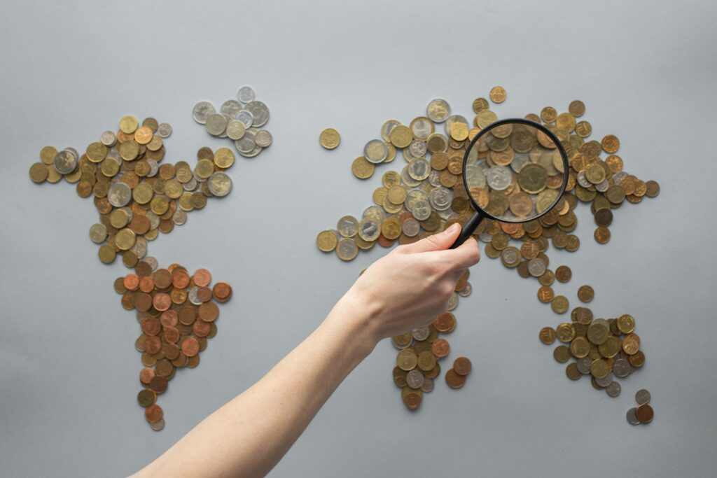 saving on international trips with woman's hand reaching over world map of coins 